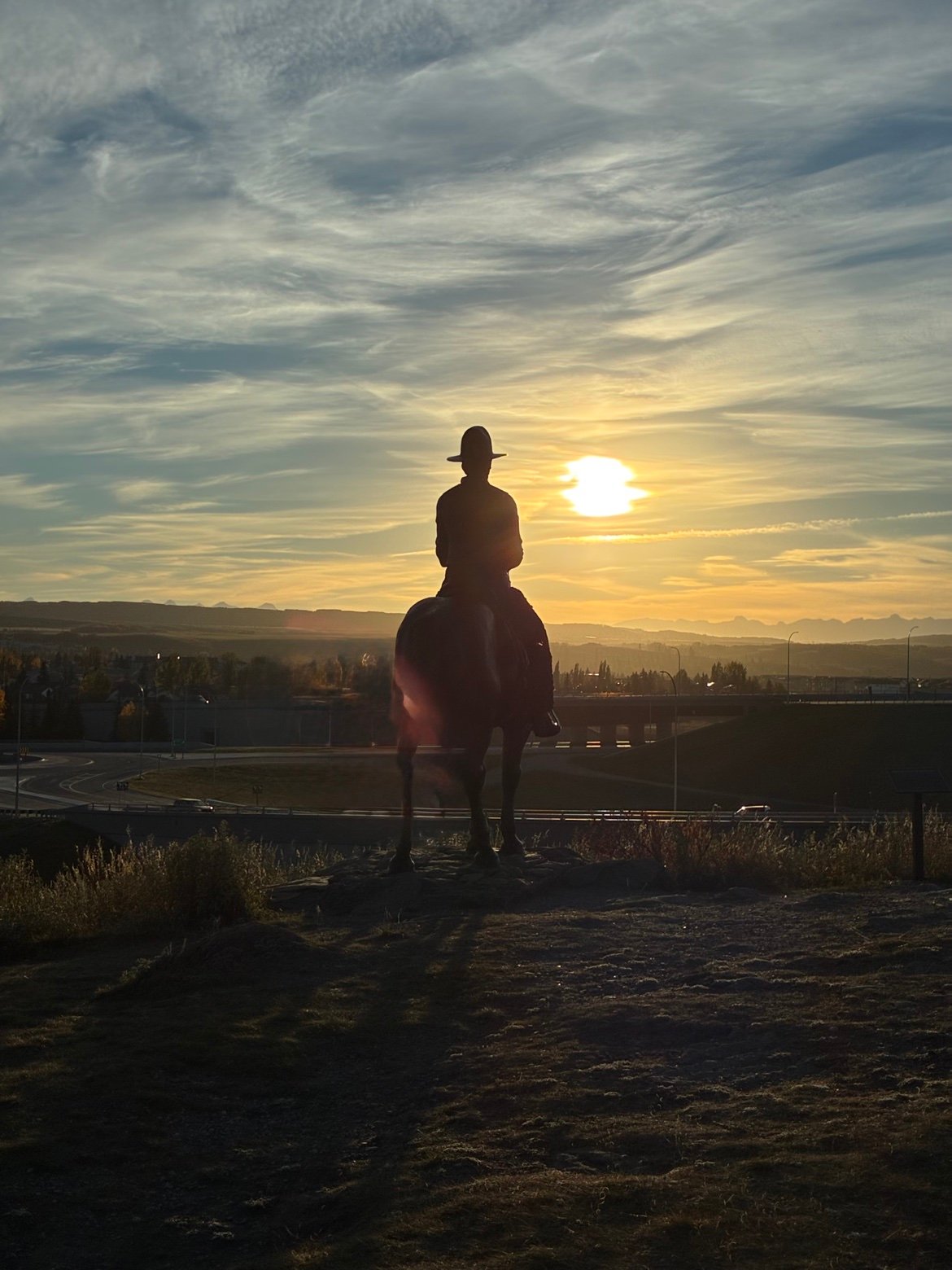Cowboy statue at sunset in Cochrane